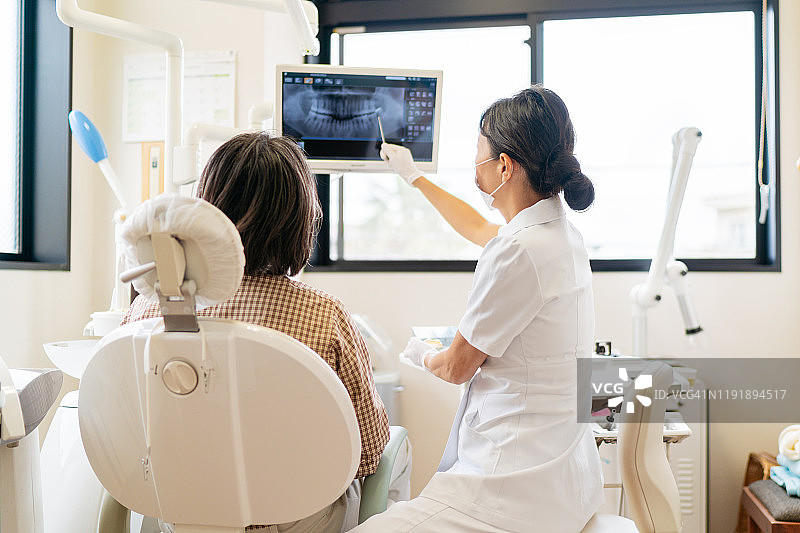 女牙科医生向病人讲解X光片图片素材