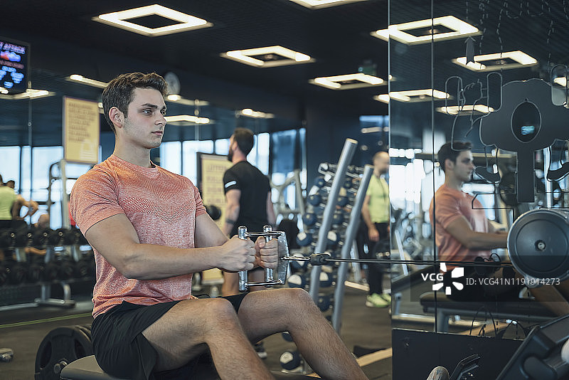 健身教练在健身俱乐部进行坐姿划船训练图片素材