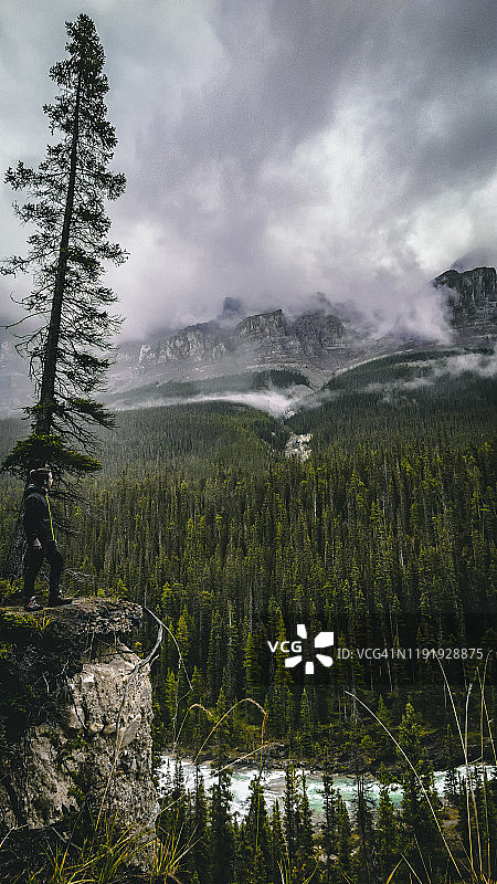 站在加拿大落基山脉米斯塔亚峡谷悬崖上的青少年男孩图片素材