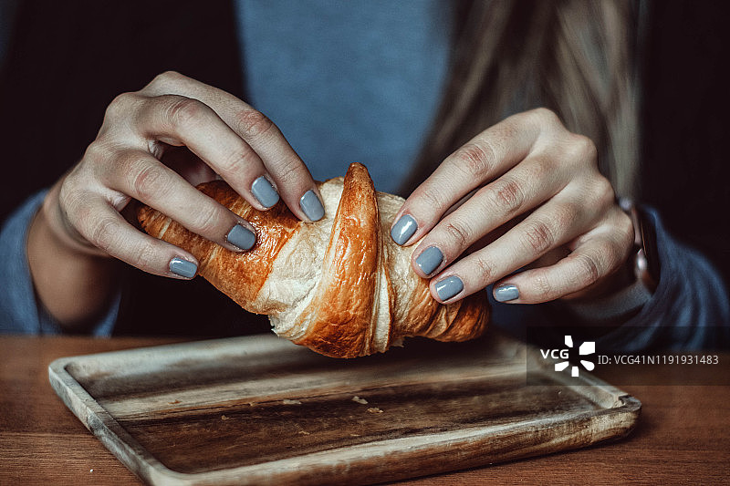 女人撕开甜牛角面包图片素材