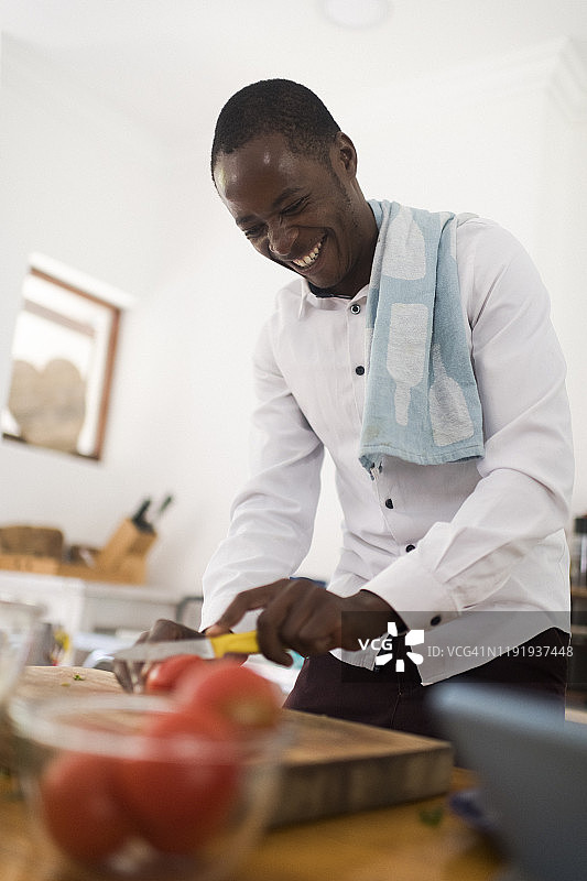 在厨房里切番茄的微笑男人的仰视图片素材