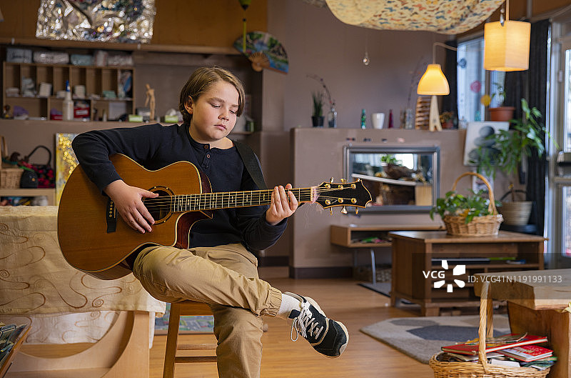 教室里抱着原声吉他的年轻音乐学生。图片素材