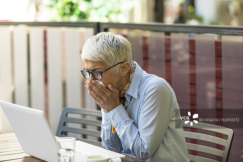患有过敏问题的老年妇女用纸巾擦鼻子图片素材