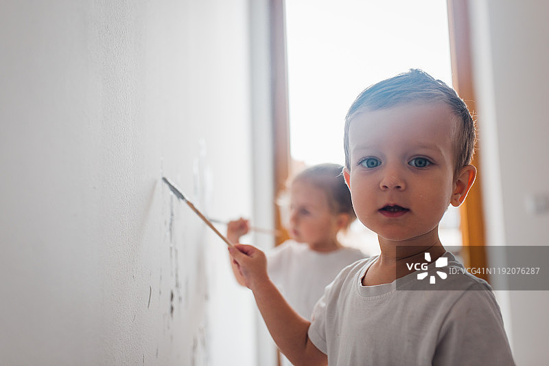 双胞胎兄妹在房间里粉刷墙壁图片素材