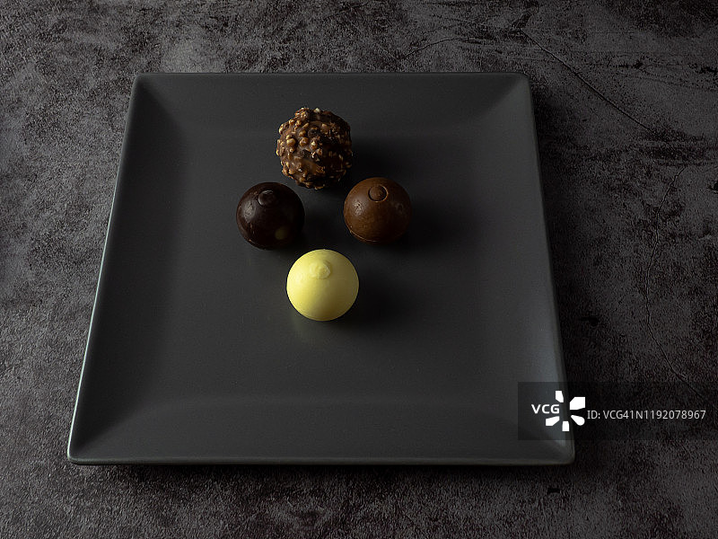 灰色方盘中的黑巧克力、牛奶巧克力、白巧克力和脆皮巧克力图片素材