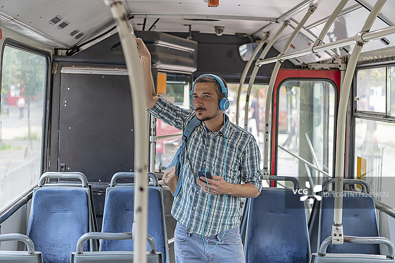 戴着耳机在公交车上听音乐的年轻男人图片素材
