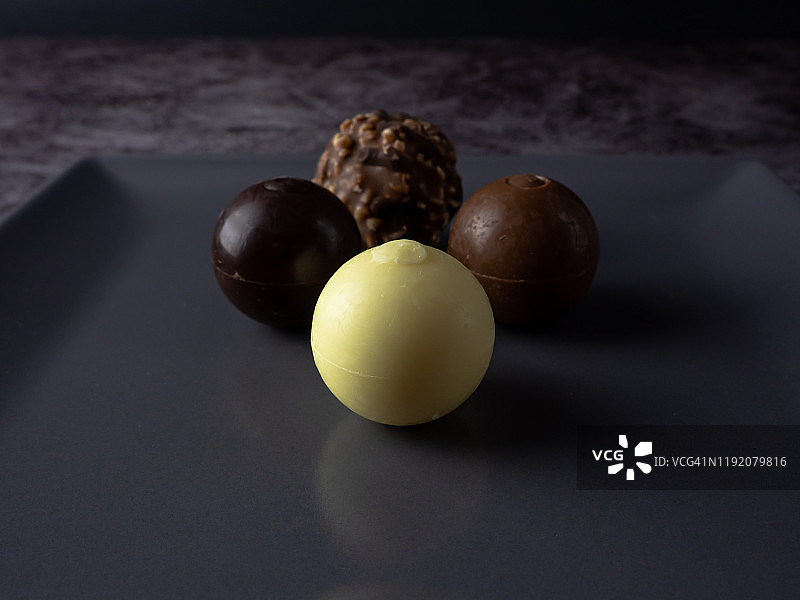 灰色方盘中的黑巧克力、牛奶巧克力、白巧克力和脆皮巧克力图片素材