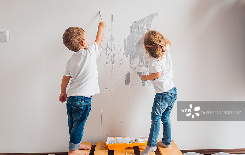 双胞胎兄妹在房间里粉刷墙壁图片素材