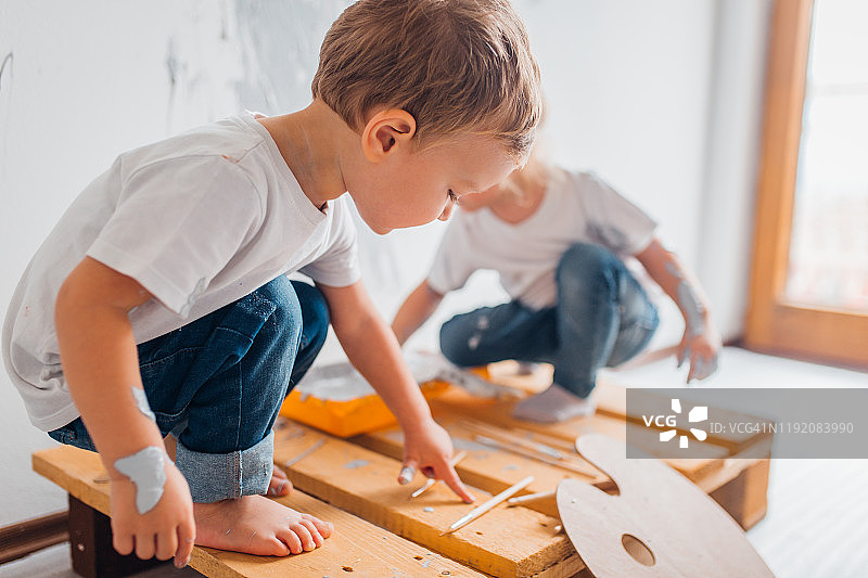 双胞胎兄妹在房间里粉刷墙壁图片素材