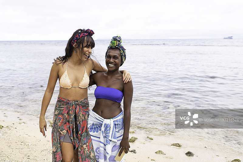 两个年轻女人在海滩上一起欢笑图片素材