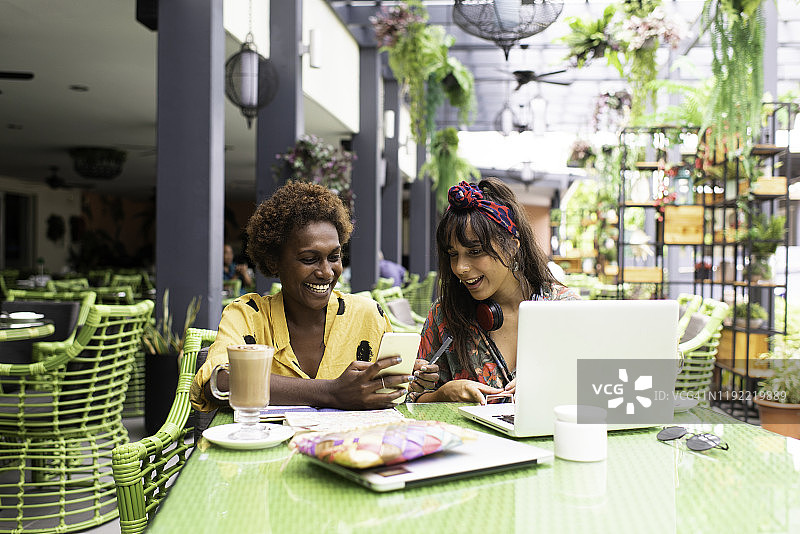 在咖啡馆用笔记本电脑工作的年轻女性朋友图片素材