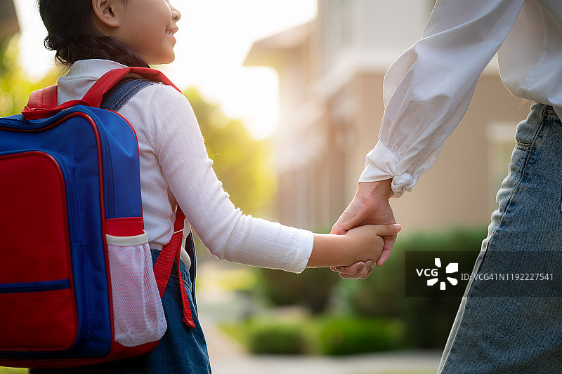 快乐亚洲母女送女儿上学。图片素材