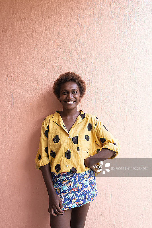 一个在粉色墙前微笑的年轻女人图片素材