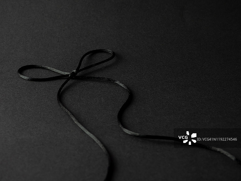黑色背景上缠绕的明亮黑色丝线蝴蝶结图片素材