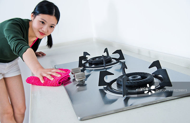 年轻的家庭主妇用粉红色的抹布清洁厨房图片素材
