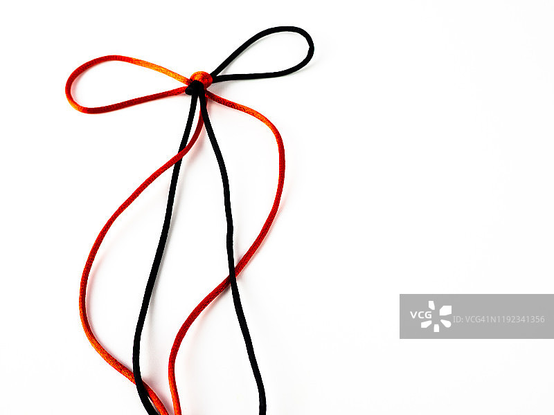 白色背景上缠绕的鲜红色和黑色丝线蝴蝶结图片素材