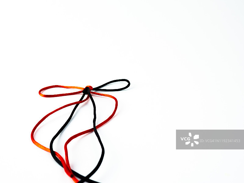 白色背景上缠绕的鲜红色和黑色丝线蝴蝶结图片素材