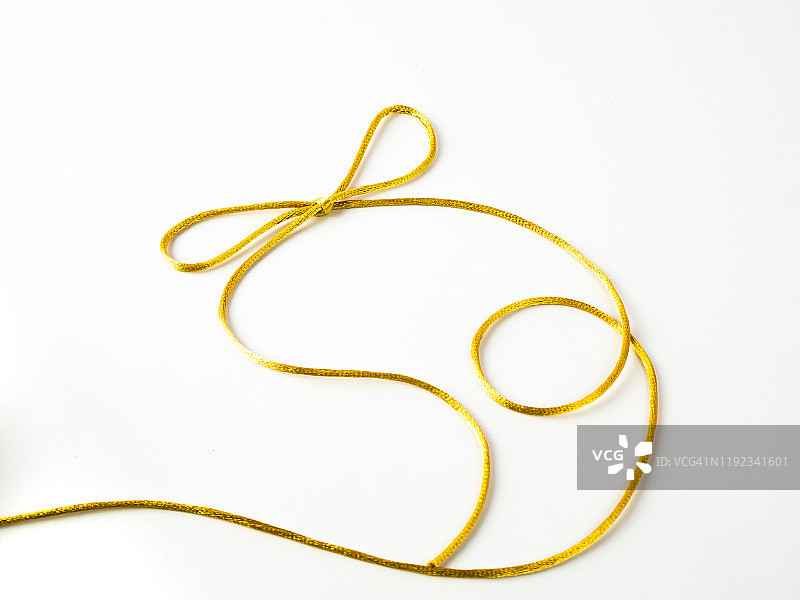 白色背景上缠绕的金色丝线蝴蝶结图片素材