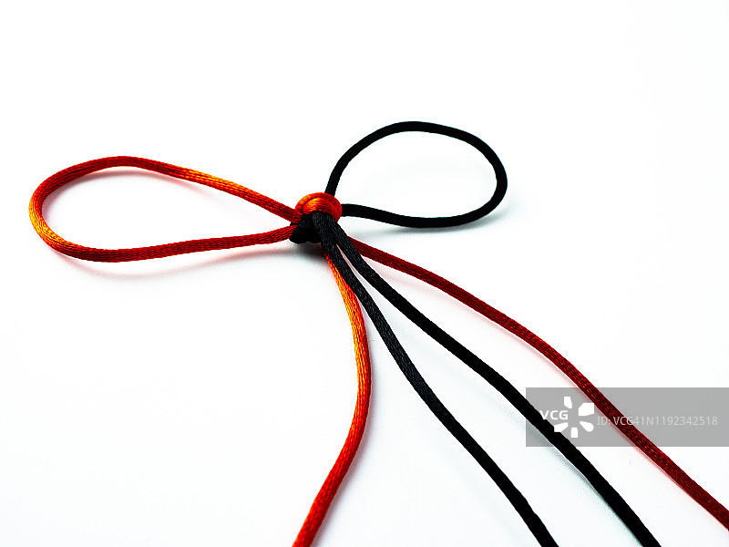 白色背景上缠绕的鲜红色和黑色丝线蝴蝶结图片素材