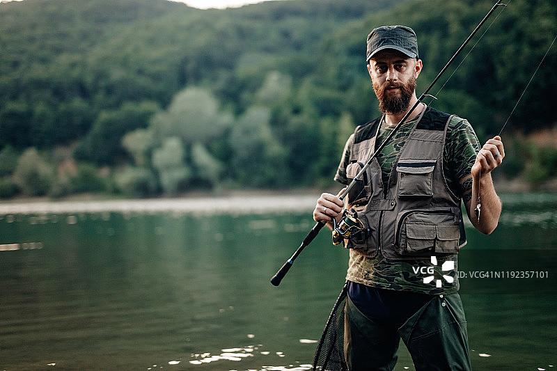 渔民站在河边手持钓竿图片素材