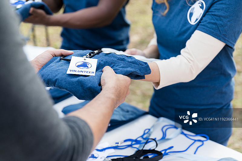 志愿者在慈善活动中分发志愿者T恤图片素材