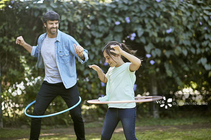 在后院挥舞铁环的微笑父女图片素材