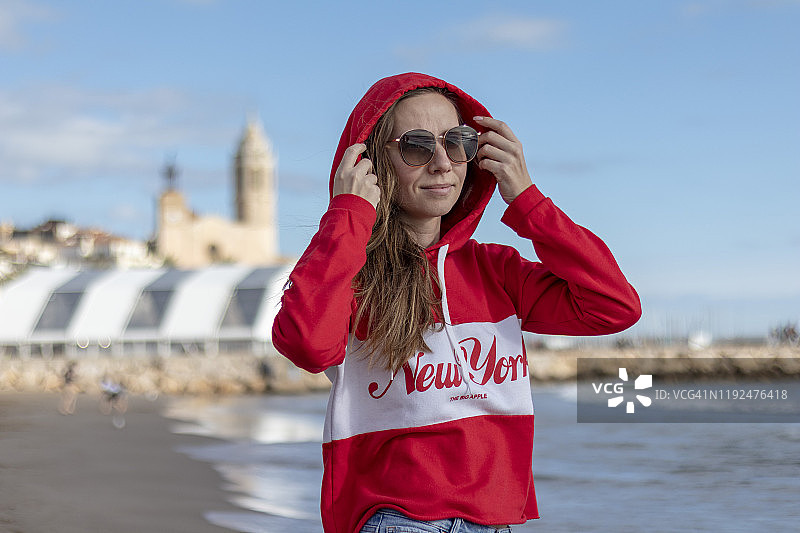 穿着红色套头衫的漂亮金发女孩在海滩上图片素材