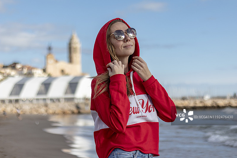穿着红色套头衫的漂亮金发女孩在海滩上图片素材
