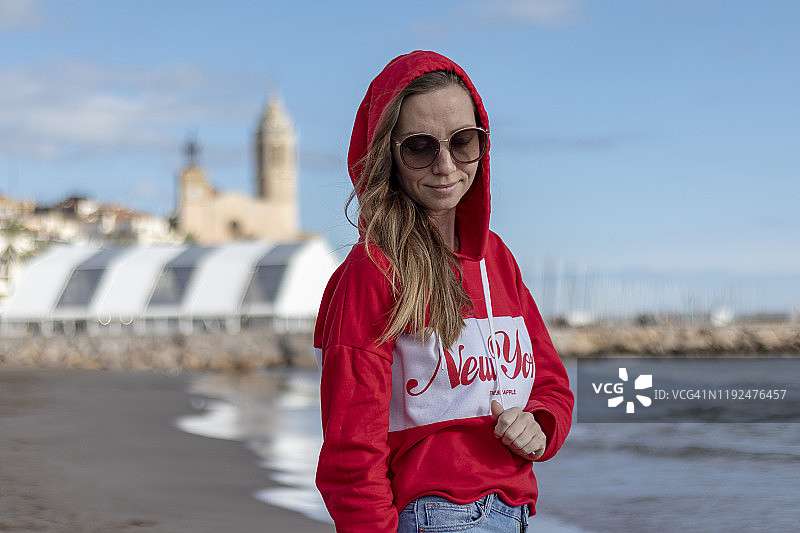穿着红色套头衫的漂亮金发女孩在海滩上图片素材