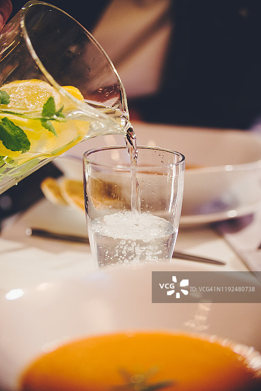 从罐中向放有汤的餐桌上倒水的特写图片素材