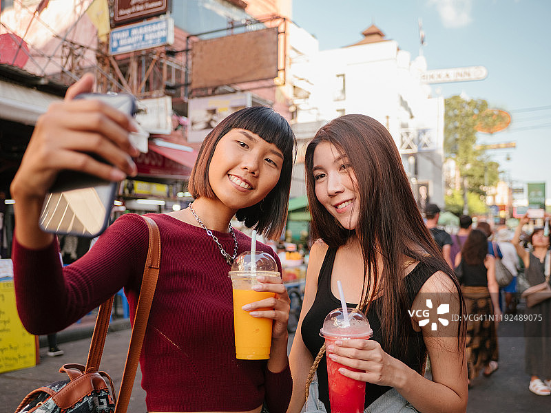 年轻的朋友们在步行街自拍并喝果汁图片素材