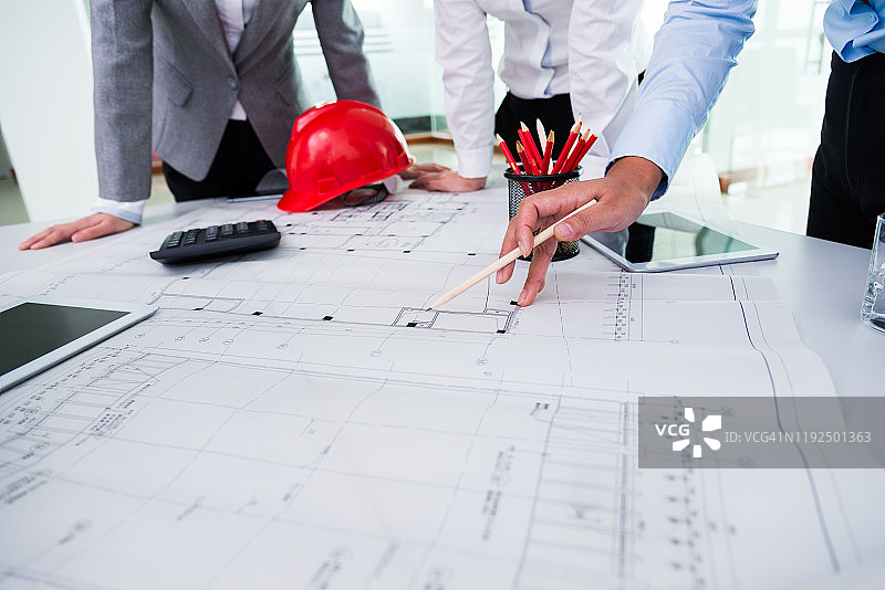 一群建筑师和工程师围坐在桌旁讨论施工计划图片素材