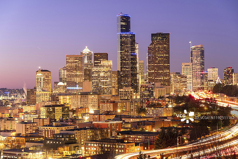 西雅图城市天际线在黄昏时被照亮，高速公路上的车灯在移动。图片素材