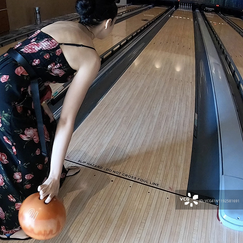 年轻女人在保龄球馆手持并投掷保龄球图片素材