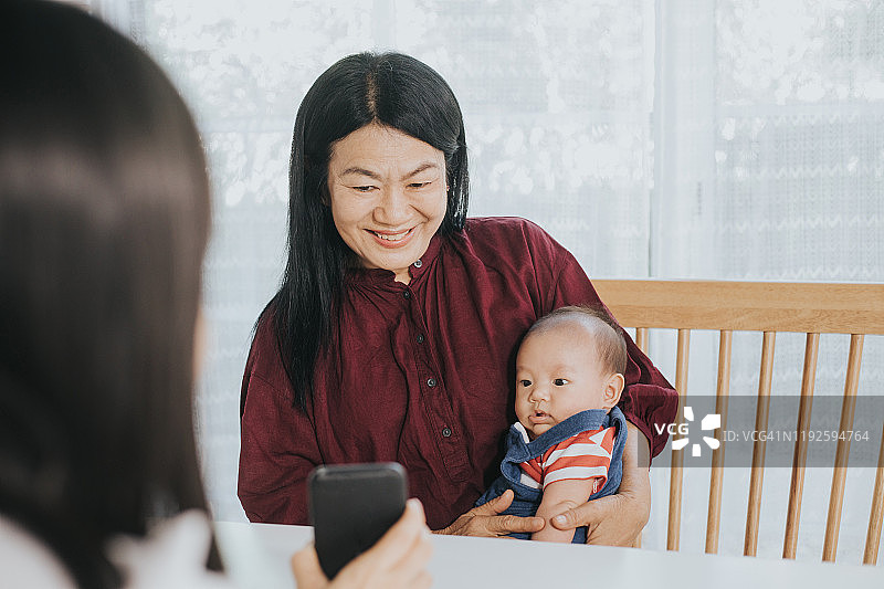 泰国奶奶在视频会议中照顾孙子，对面是他的母亲图片素材