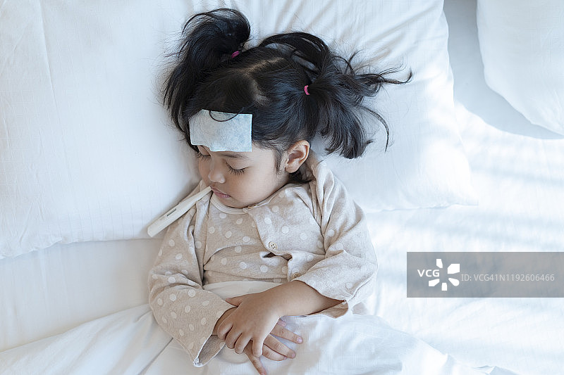 医疗检查与治疗概念。母亲正在测量亚洲小女孩的体温。生病的孩子发烧卧床图片素材