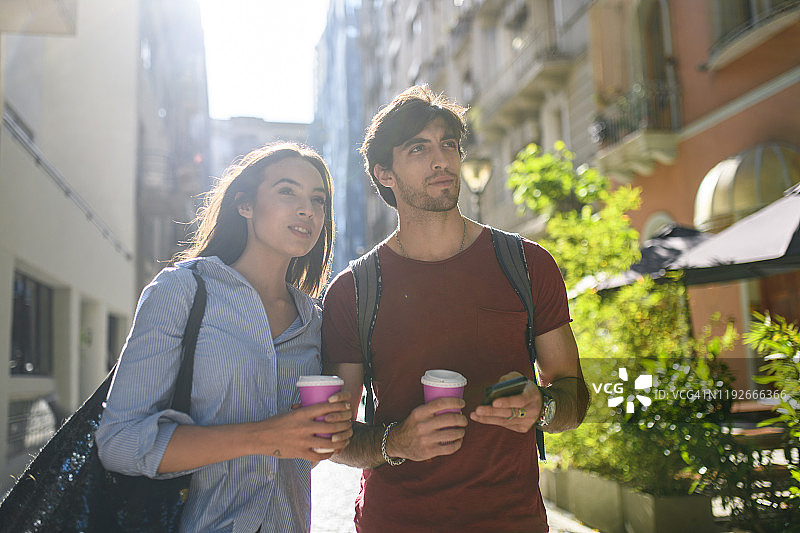 游客喝着咖啡查看智能手机上的路线图片素材