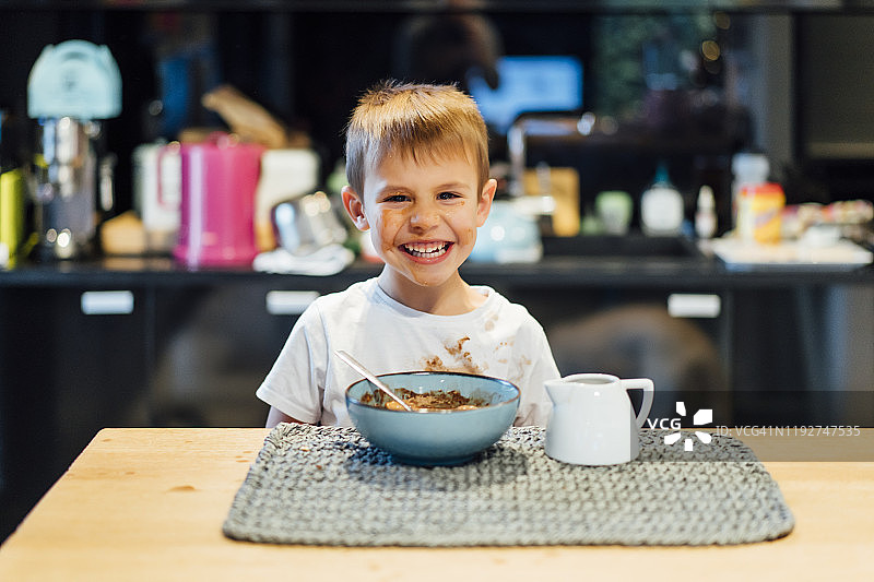 有趣的小孩吃早餐麦片弄脏了脸图片素材