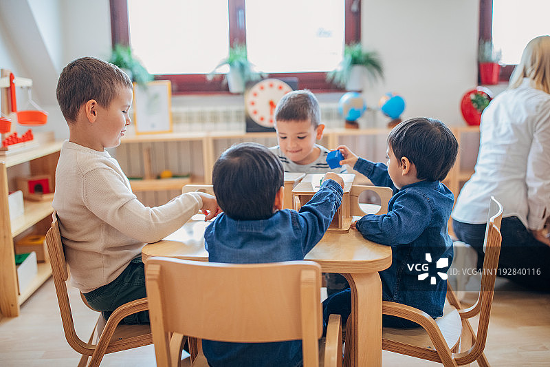 学龄前男孩们在幼儿园教室里一起玩耍图片素材