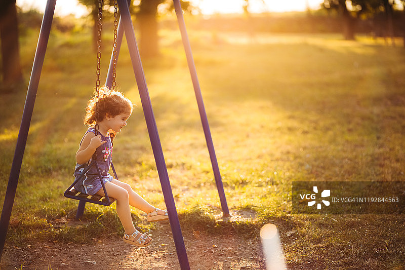 小女孩在日落时荡秋千图片素材