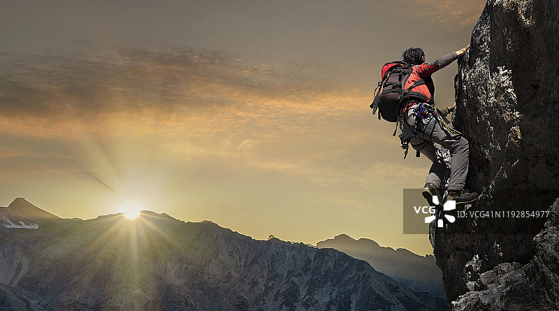 日落时分在岩壁上的登山者图片素材