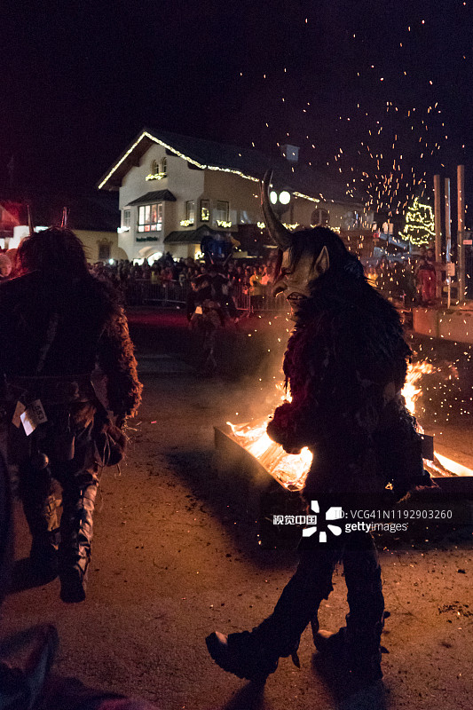 男子在卡普伦的Krampuslauf传统公共表演中戴着Krampus面具，背景是火焰图片素材