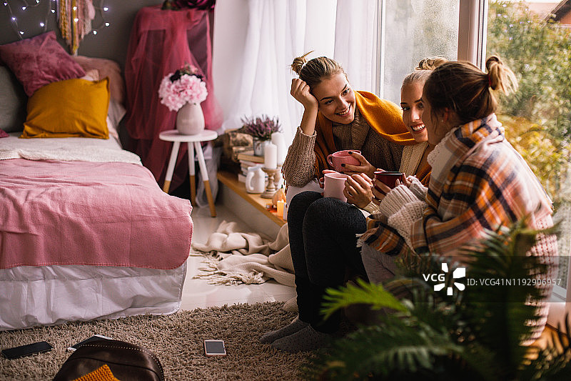 三名微笑的女子身穿冬装分享热饮图片素材
