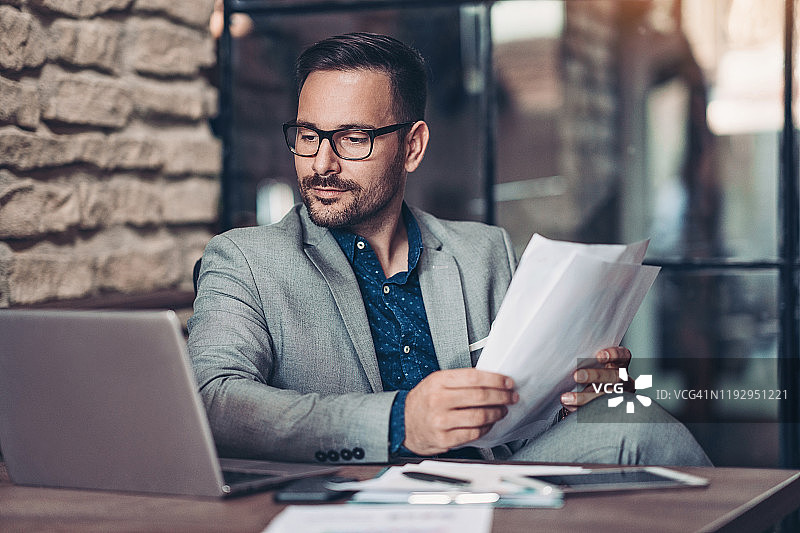 手提笔记本电脑和文件的严肃商人图片素材