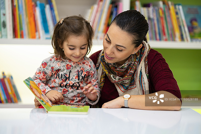 可爱的女孩和她的母亲在读图画书图片素材