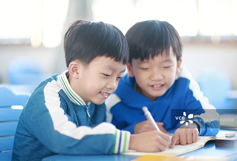 小男孩在教室里的书桌前看书图片素材