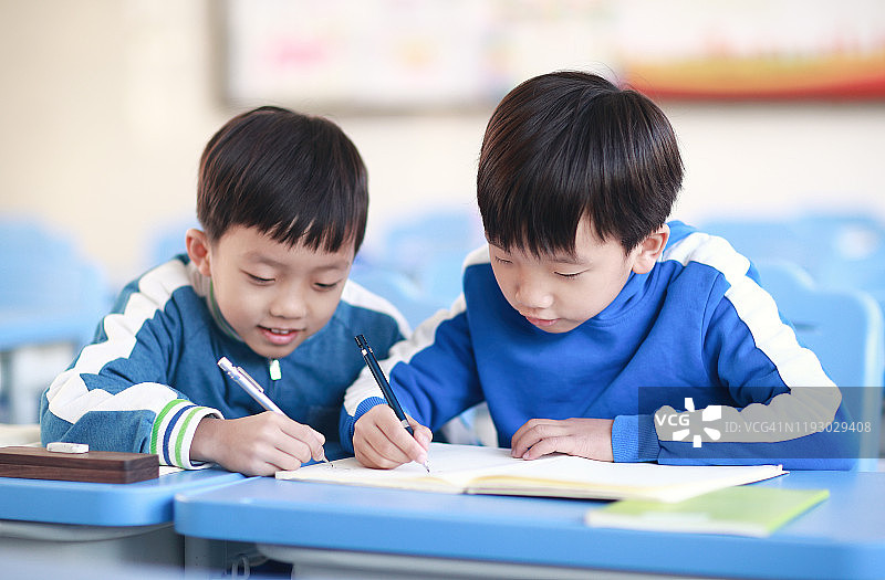 小男孩在教室里的书桌前看书图片素材