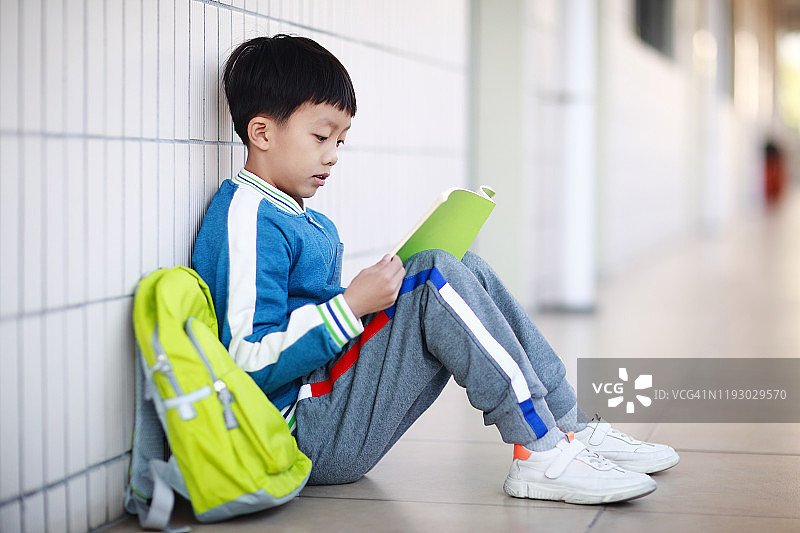 小男孩在教室里的书桌前看书图片素材