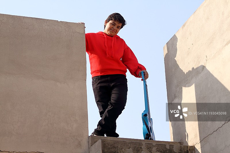 抱着吉他站在楼梯上的小男孩图片素材