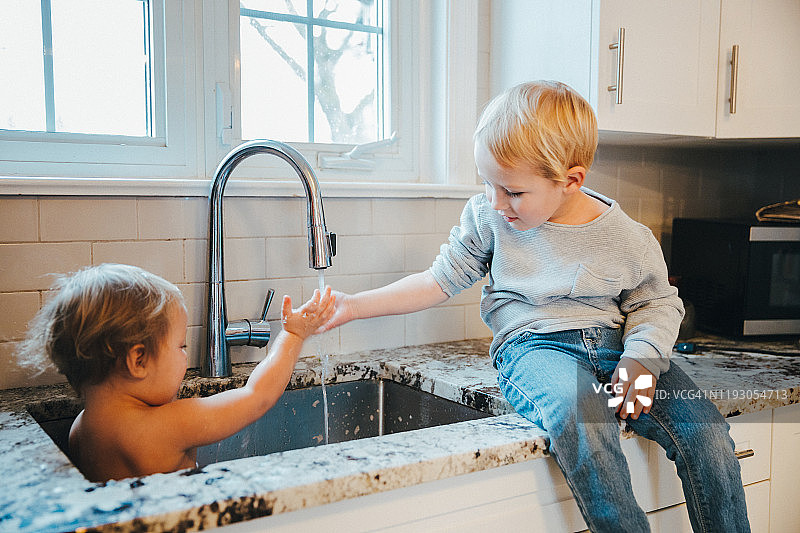 兄妹在厨房水槽里玩耍图片素材